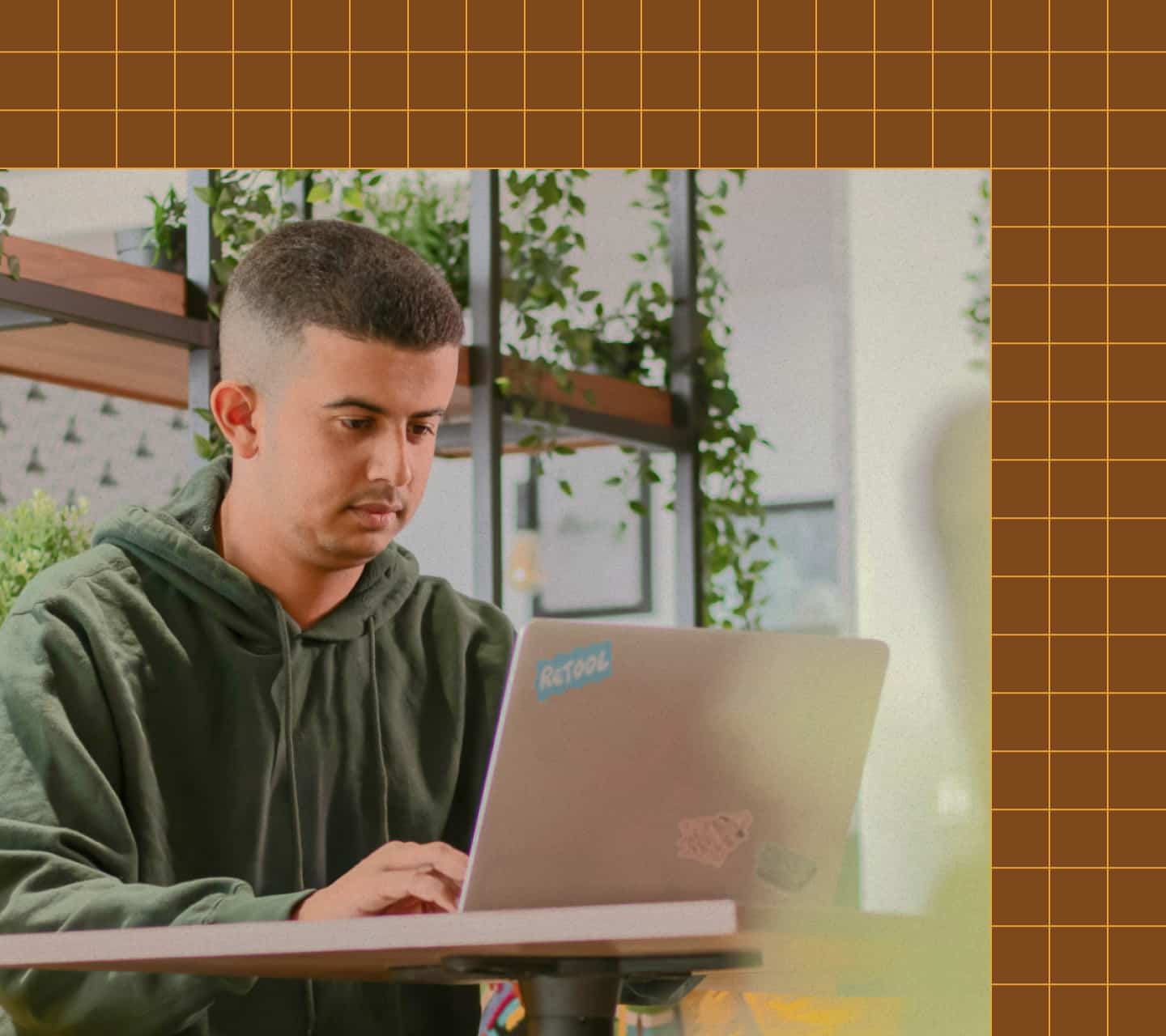 A person working on a laptop with a Retool sticker, seated at a desk working at an agency.